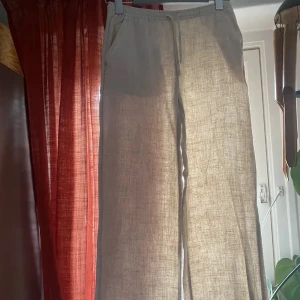 Beiga linnebyxor från Nelly - Snygga och bekväma beige linnebyxor från Nelly. Byxorna har en avslappnad passform med elastisk låg midja och en bakficka. Perfekta för en stilren och luftig look. säljer då de var lite för korta på mig säljer även ett par i s inga defekter