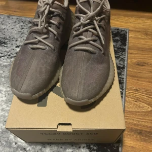 Adidas Yeezy Boost 350 i mono mist  - Säljer ett par Adidas Yeezy Boost 350 i en brun nyans. Skorna har en stickad ovandel, rund tå och snörning. Sulan är ribbad och ger en sportig look. Perfekta för dig som gillar streetwear och vill ha något bekvämt och snyggt.