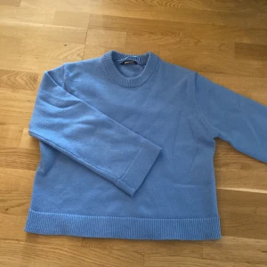 Ljusblå stickad tröja från Gina Tricot - Säljer en ljusblå stickad tröja från Gina Tricot. Tröjan har rund halsringning, långa ärmar och bred ribbad kant vid ärmslut och nederkant. Perfekt för lager-på-lager och enkel att styla till olika outfits.