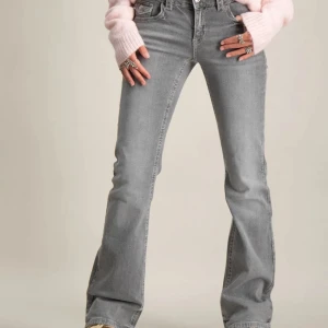 Grå bootcut jeans med fickdetaljer - Säljer ett par grå bootcut jeans med snygga fickdetaljer bak och klassisk femficksdesign. Jeansen har normal passform och är tillverkade i denim med lätt stretch. Perfekta för dig som gillar en tidlös look med lite extra edge.