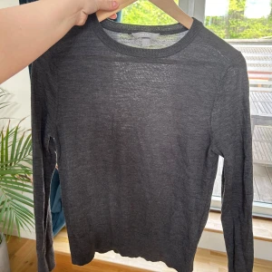 Mörkgrå tunn stickad tröja i 100% merinoull - Säljer en mörkgrå, tunn och mjuk stickad tröja från Arket i 100% merinoull. Tröjan har rund halsringning och långa ärmar, perfekt för lager-på-lager under kyliga dagar.