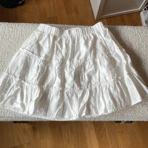 Vit volangkjol från FB Sister och är köpt på Newyorker  - Säljer en söt vit kjol frånF B Sister i storlek XS.Kjolen har flera volanger och resår i midjan för en bekväm passform. Perfekt för varma dagar och enkel att matcha med olika toppar. Kjolen är använd 1-2 gånger och är köpt på newyorker förra året.💕