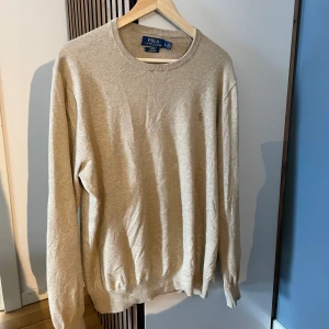 Beige pullover från Polo Ralph Lauren - Säljer en beige långärmad tröja från Polo Ralph Lauren i slim fit-modell. Tröjan är tillverkad i mjukt stickat pima-bomull och har en diskret broderad logga på bröstet. Hör av er🙌 pris ej hugget i sten✅ Storlek L men slimfit och passar M 