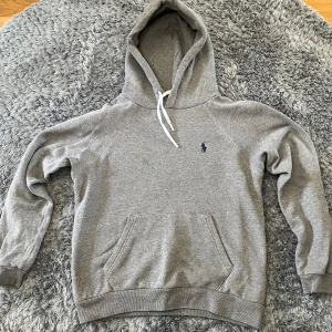 Grå hoodie från Polo Ralph Lauren - Klassisk grå hoodie från Polo Ralph Lauren. Perfekt för en avslappnad stil.