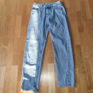 Ljusblå jeansbyxor från Weekday - Säljer ett par ljusblå raka jeans från Weekday med klassisk femficksdesign och normal passform. Byxorna har knappgylf och är tillverkade i bomull. Storleken är W27 och L32