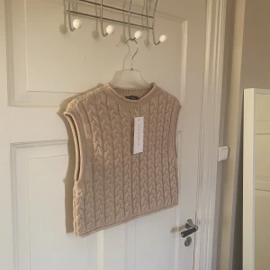 Stickat väst från Chiquelle  - Säljer denna snygga västen från Chiquelle. Stickat och ganska kort modell. Storlek One Size, passar bäst som XS. Helt ny och prislappen sitter kvar. 100% bomull. 