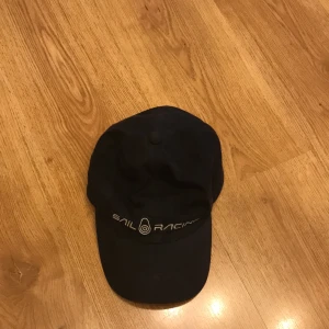 Sail Racing Keps - Rätt så använd Sail Racing keps som jag säljer för att det ej är min stil längre. Går att justera storlek där bak och vet inte riktigt vad det är för storlek generellt. Lite färg har försvunnit pga solen men det är inget som man tänker på. Köpt på NK 