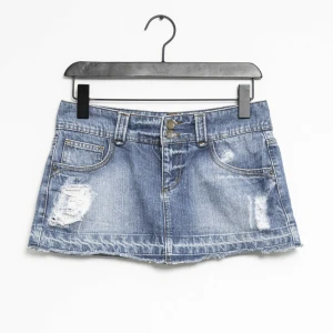 Lågmidjad jeanskjol  - Säljer nu denna ur-snygga lågmidjade jeanskjolen med snygga slitningar. Aldrig använd så nyskick! Storlek 38 men skulle säga mer som 34/36. Har inga bilder med den på då den tyvärr är för liten för mig. Perfekt i sommar!! 