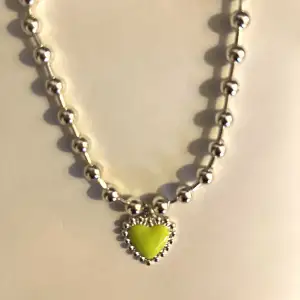 Fint halsband från weekday. Silverfärgad med ett hjärta i lime grön färg.  Aldrig använd så är i nyskick