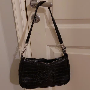 Svart baguettväska - Svart baguettväska från glitter med ormskinns textur och silver detaljer. Knappt använd och har inga fel