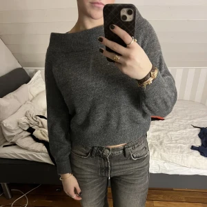 Grå stickad tröja - Säljer denna jättefina mörkgråa stickade tröjan med lite off-shoulder. Fint skick, använd fåtal gånger. Buda från 200kr