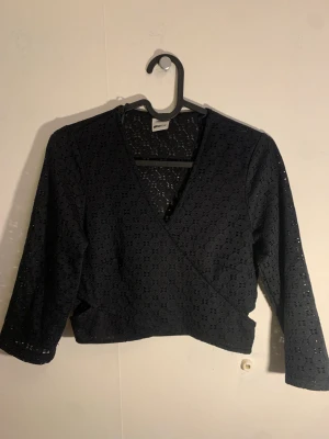 Wrap topp - Svart, tunn magtröja är kort och sitter som en wrap, ovaler i mönster.
