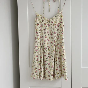 Klänning - Söt blommig sommarklänning, använd väldigt få gånger. Knyts där bak med snören och har en diskret dragkedja. Tyvärr passar den inte så bra för den med lite större byst, därför jag säljer den! 