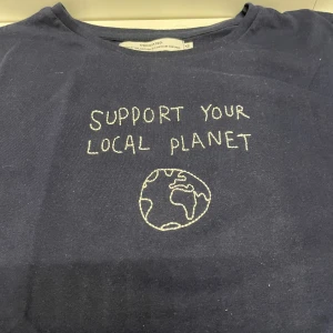 T-shirt ”support your local planet” - Säljer en t-shirt med tryck där det står ”support your local planet” med en jordglob. Tröjan är för stor för mig och därför helt oanvänd! Jag skulle säga att den är i strl S då jag på bilden är en XS. Betalning sker via swish, hör gärna av dig vid frågor💞