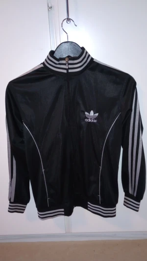 Äkta Adidas  - Storlek M, svart med silver färgade revär.Adidas märke på bröstet samt ryggen. knappt använd så den är som ny skick. kan posta finns i Upplands Väsby 