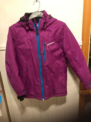 Skidjacka Everest  - Skön varm skidjacka/vinterjacka av mycket bra kvalitet. Flera fickor, kardborreband vid handleden, avtagbar huva. Mycket obetydligt använd. Storlek 152 kan jämföras med en XS . Det finns även ett par svarta termobyxor storlek 146 om du är kort och liten. 