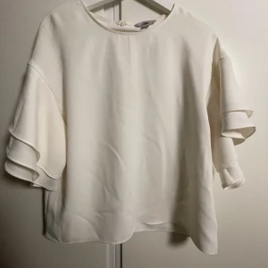 Blus - Vit blus med volanger på ärmarna. 