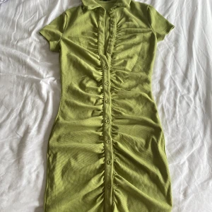 klänning - grön klänning med användbara knappar. går till mitten av låret på mig som är 173 cm. storleken är 36. köparen står för frakt.