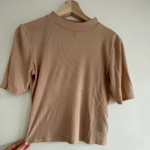 Beige t-shirt - En beige t-shirt från HM. Ribbat material. Liten polokrage. Storlek S. Väldigt härligt och skönt material. Säljer då den inte kommer till användning. Pris kan också diskuteras. Frakten är inräknat i priset😊🌸