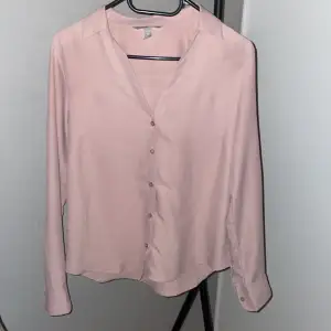 Rosa skjorta/blus med v-ringning från H&M i storlek S. Använd endast en gång, i gott skick. 