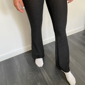 Svarta byxor med bootcut - Svarta glittriga byxor/leggings med bootcut från Gina Tricot.  Personen på bilden är 168cm lång och bär strl S