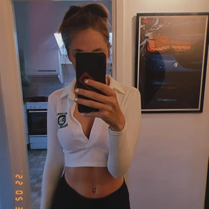 Vit croptop - Vit med grönt tennis emblem vid vänstra axeln. Storlek S. 