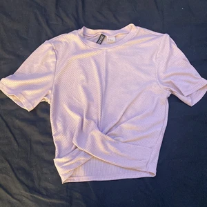 H&M (DIVIDED)  - En t-shirt med material. Har hållt väldigt bra, ej nopprig. Bra skick, slutar straks över naveln. Ljus lila färg. ”OBS den finns att köpa i ljus rosa fast långärmad!” Båda är väldigt luftiga. Båda är i samma storlek!!