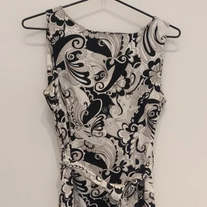 Jättefin klänning i 60-talsstil i snyggt svartvitt mönster. - Tight modell, dragkedja i ryggen och knytskärp i midjan  Material 97% bomull  3% elastan  Sparsamt använd och i gott skick.  