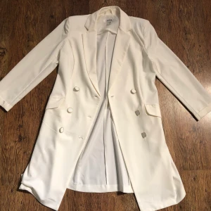 Off-white kappa från Amisu  - Off-white kappa från Amisu i storlek 38. Ej använd då det vart en present som inte är i min stil. Har fickor som måste sprättas upp och vadderade axlar. Ganska tunt material och passar till vår/sommar men även inomhus!  Inga defekter.