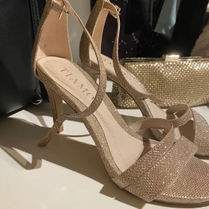 Guldglittriga klackar & handväska  - Säljer mina klackskor från Tiamo och Handväska från Kristina Brud och fest. Perfekt att ha tillsammans på balen! Klackar: 600kr väska: 400kr (Endast använt 1 gång under min bal)