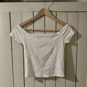Vitt offshoulder topp  - Tight fit men med hög stretch på tyget. Vitt/benvitt i färgen, lite smått off shoulder. Storlek S. 