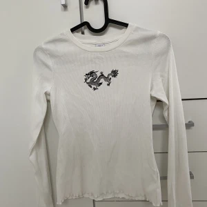 Vit långärmad tröja med en drake - En jätte fin vit långärmad tröja med en drake på! Aldrig använt! 