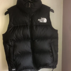 RETRO NUPTSE DOWN GILET  - Köpt för 3500 på TNF i Milano säljer för 1000 Storlek S. Två fickor med dragkedja + en till ficka med dragkedja på insidan. Västen har en tunn luva under kragen man kan dra upp. 