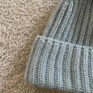 Mössa  - Ljusblå mössa med inslag av ”glitter” från & order stories. Knappt använd och är som ny.