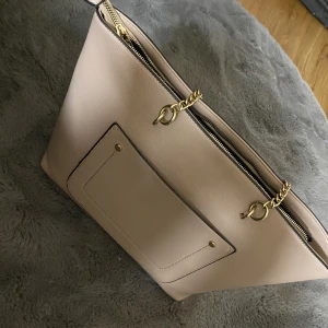 Modeväska - En stor väska där dator och annat material får plats. Finns små fickor inuti där man kan lägga saker som lätt försvinner. 