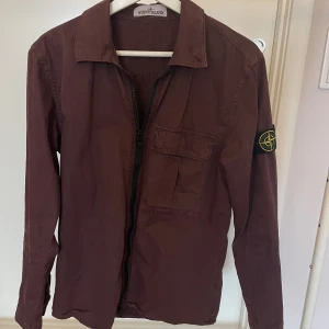 Stone Island jacka strl S - As snygg Stone Island jacka/överskjorta i vinröd i storlek S. Jackan är i väldigt bra skick, en perfekt vår och sommarjacka. Jackan är i herrmodell och herrstorlek. Nypris runt 3000kr, säljes för 1500kr. Köpt på NK i Göteborg, kvitto finns!