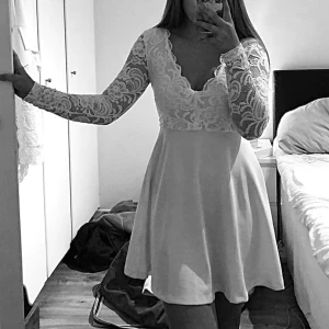 Vit klänning  - Säljer min vita klänning då den endast är använd någon enstaka gång och sedan dess bara hängt i garderoben. Spets upptill och tjockare vitt tyg nedtill. Mått från axel och ned: ca 81cm.