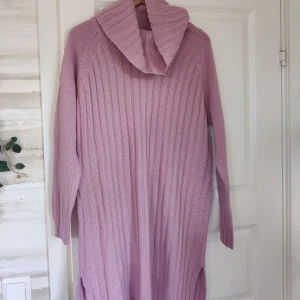 Tjock stickad klänning  - Oanvänd, varm & gosig stickad tjocktröja/klänning med slits i sidorna. Färgen är en dammig lilarosa, typ mauve. 