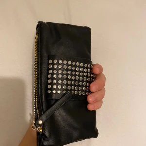 Handväska - En sjukt fin handväska, där man kan ha t.ex sin mobil, lite smink,kort å kanske nycklar. Denna får plats med mycket eftersom den har två fack med mycket plats åt sidorna för pengar eller bankkort. (Köparen står för frakten)