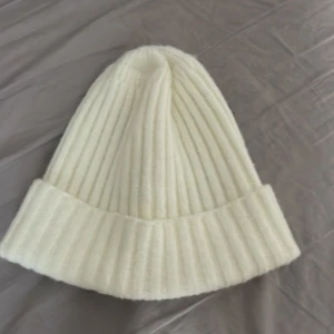 mössa - En vit mysig mössa. Aldrig använd 55-59cm omkrets 21 cm höjd 