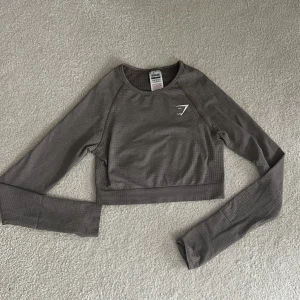 Gymshark crop top - Crop top med lång sleeve från gymshark. Den har en lila/grå färg som är lite svår att se på bilden. På den sista bilden kan ni se passformen. Köpt för 449kr. 