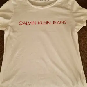 Säljer 2 st vita t-shirts av märket Calvin Klein.  1. Köpt på Kids Brand Store, bra skick utan märken, storlek 164/176. Vit med svart CK tryck. 2. Köpt på Johnells, bra skick utan märken, storlek S (dam), vit med röd tryck.  Säljs endast tillsammans. 