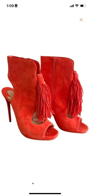 Christian Louboutin Orange Suede Heels - Fringe tassel. Suede shoe crafted with cutouts in ankle boot-inspired silhouette Side-zip with cutout heel and exposed arch 13CM Stiletto Heel Tagged Size 38.5 Made in Italy Barely worn, original red sole. Minor  wear on suede, overall good condition