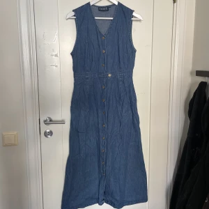 Jeansklänning - Fin jeansklänning (med fickor!!) tidigare köppt secondhand. Guldiga knappar med solar på. Obs den är inte fläckig det är skuggor!