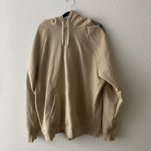 Hoodie - Beige hoodie med text på armen. Fint skick!