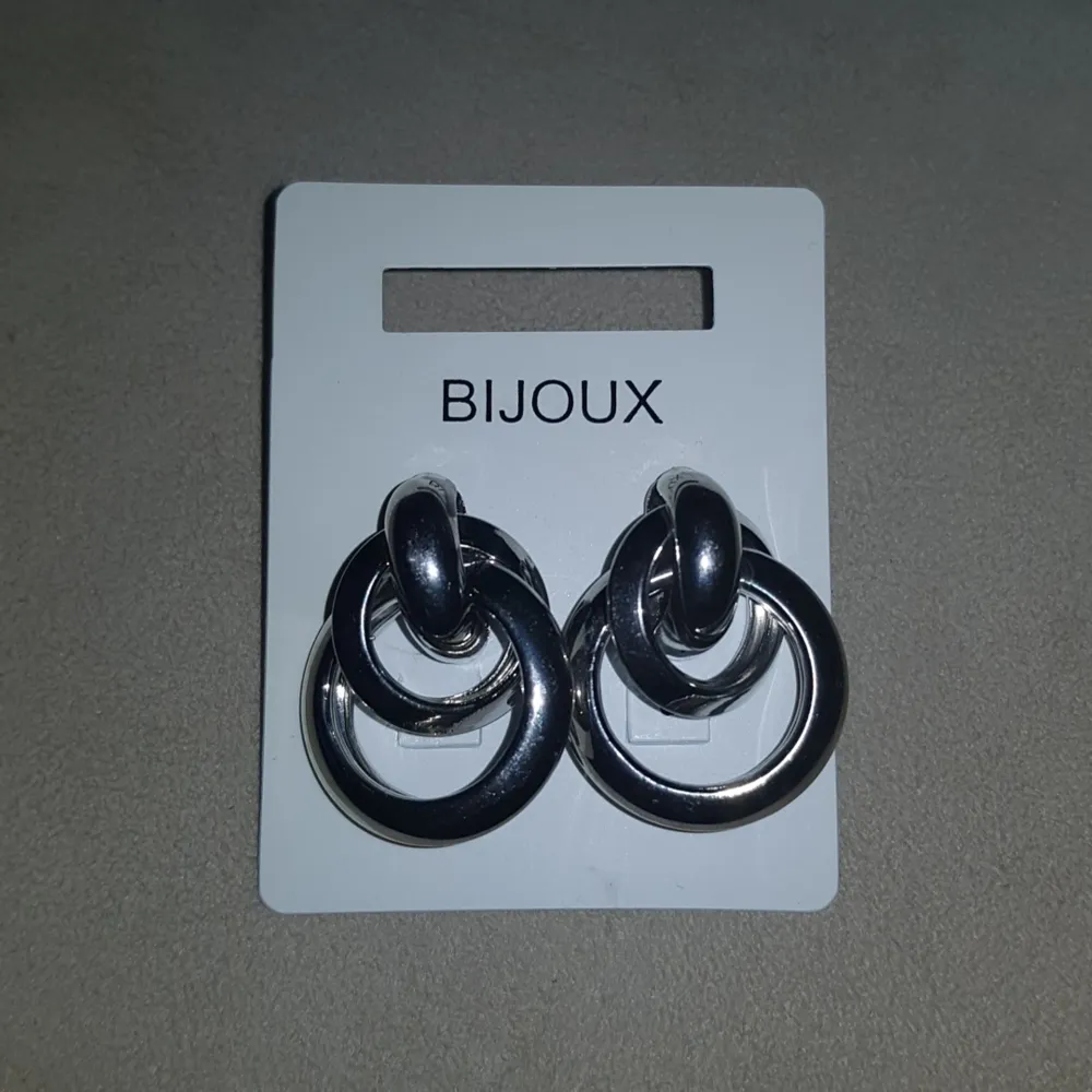Silverfärgade örhängen med ringar, cirka 2cm i diameter i stora ringen. ALDRIG ANVÄNDA!. Accessoarer.
