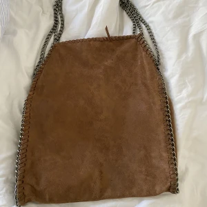 Brun väska  - Väskan är stor och har mycket utrymme. Är lite sliten på kanterna men är i annars fint skick. 