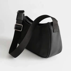 Other Stories Nylon Baguette Bag - Svart väska i bra skick (något sliten i kanterna). Nypris 750 kr. Köparen står för frakt! Kan också mötas upp. 
