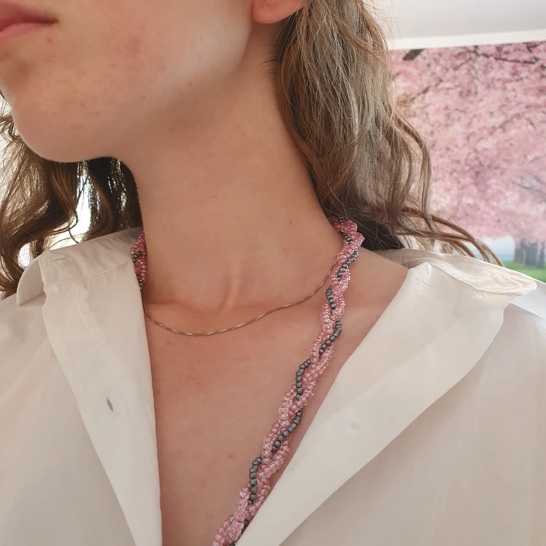 Ett flätat pärlhalsband i rosa och grått.