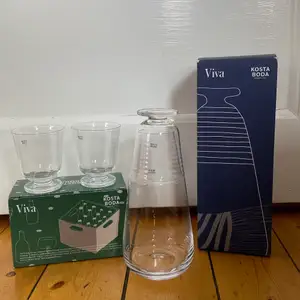 Karaff och två glas från Kosta Boda i serien Viva. Aldrig använda och kvar i förpackning. Original pris: 249 för glasen och 599 för karaffen